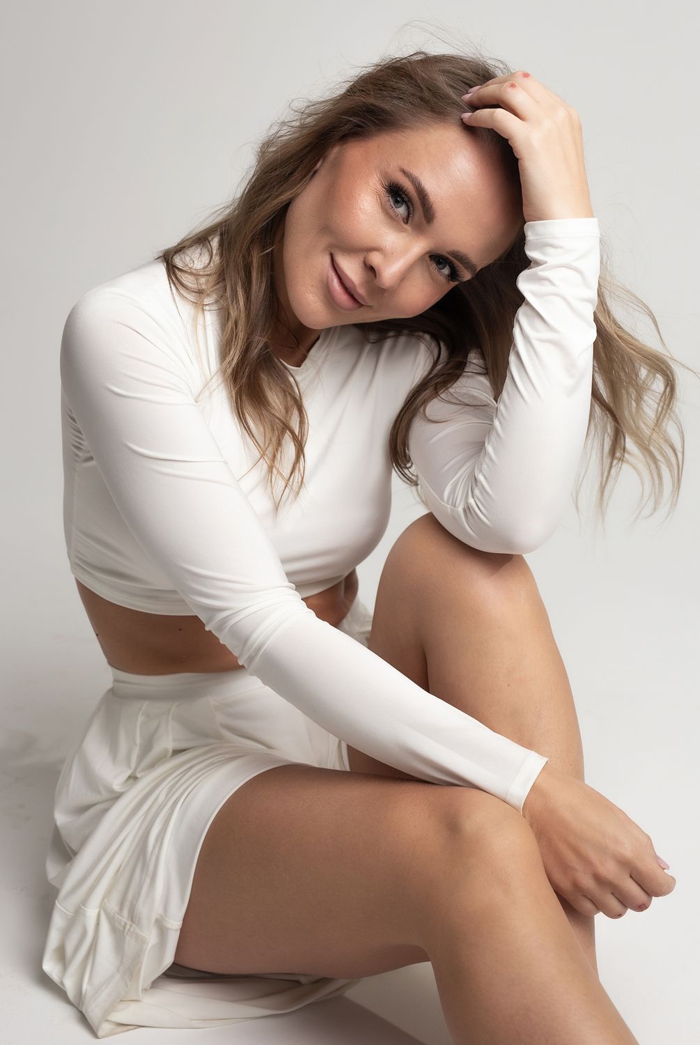 Alpharetta Vaginal Rejuvenation model in white outfit sitting and smiling.