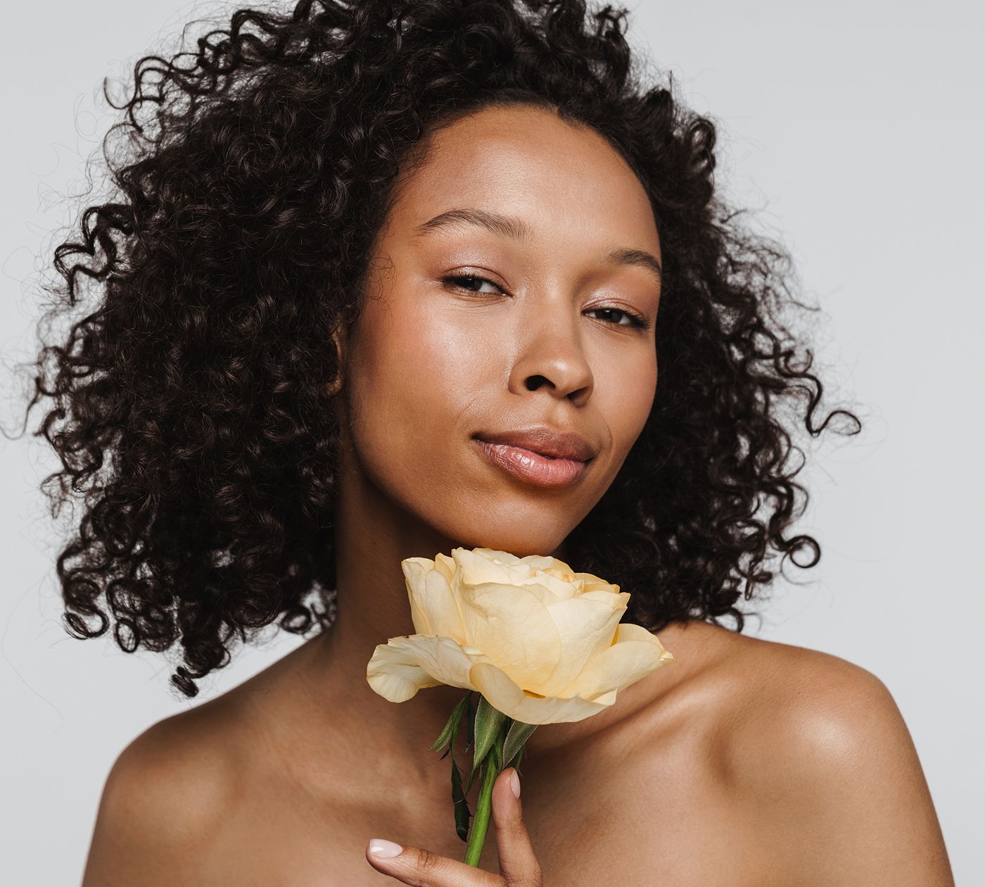 Woman with curly hair holding a yellow rose.