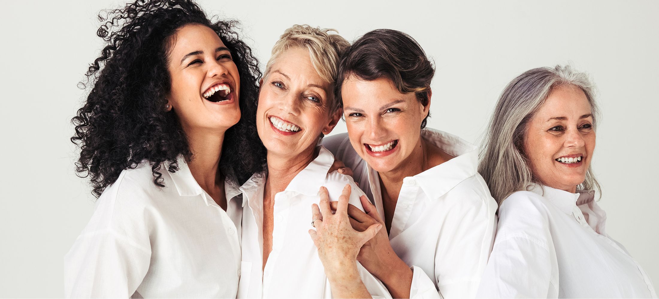 Alpharetta Women's Wellness models laughing together in white shirts\